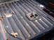 1988 Ford Bronco - Close-up of a truck bed showing a tie-down anchor and ribbed flooring, with a toolbox in the background.