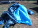 1988 Ford Bronco - Vehicle parts are covered by tarps, with a portion of a vehicle's roof visible in the background.