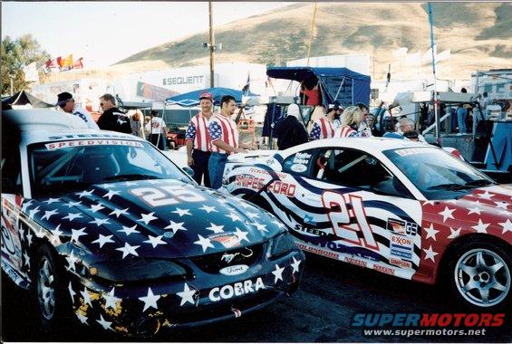 Two Ford Mustangs with stars and stripes livery, one with "COBRA" text and number 25, the other with number 21