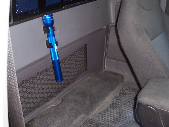 Blue flashlight mounted on the interior wall of a truck cab, next to a storage net and seat