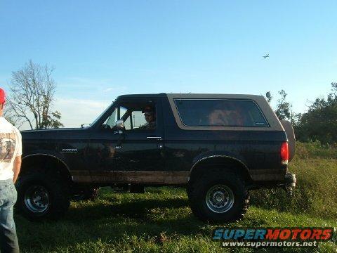 1989 Ford Bronco parked in a grassy field with a person driving