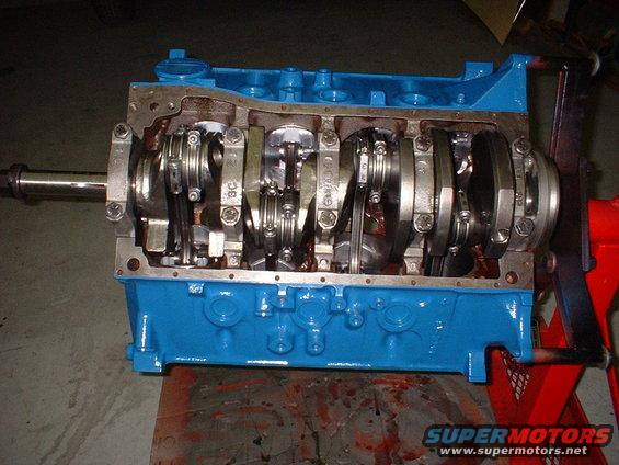 Engine block with crankshaft and connecting rods visible, painted blue. It's on an engine stand
