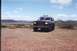 1990 Ford Bronco - A dark 1990 Ford Bronco is parked on a dirt lot with a scenic landscape in the background.