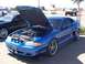 2002 Ford Mustang - A blue Ford Mustang is displayed with its hood open, revealing the engine compartment, at an outdoor car show.