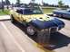 2002 Ford Mustang - A black convertible with yellow flame graphics is parked at a car show next to a sign detailing its features.