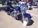 2002 Ford Mustang - A blue Harley-Davidson motorcycle is displayed at an outdoor car show, with other vehicles in the background.