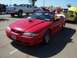 2002 Ford Mustang - Red convertible Mustang parked at a car show, with other vehicles visible in the background.
