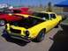 2002 Ford Mustang - A yellow 1970s Chevrolet Camaro with its hood open is parked next to a red car at an outdoor car show.