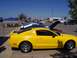 2002 Ford Mustang - Yellow Ford Mustang GT at a car show with hoods open on other vehicles.