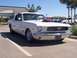 2002 Ford Mustang - A classic white Ford Mustang is parked in a lot, a prominent hood scoop and custom wheels.