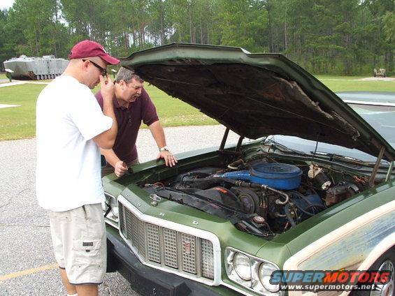 Green 1972 Ford Torino engine bay with hood open, two men examining