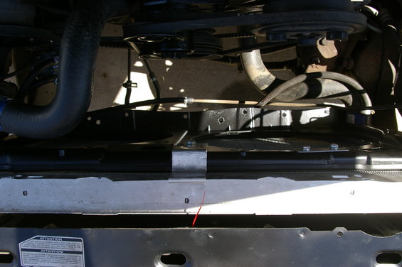 Close-up of vehicle's engine bay showing radiator and fan assembly. Visible hoses and belts