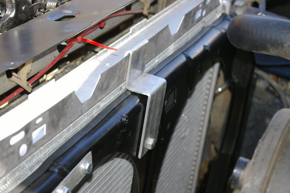 Close-up of a custom metal bracket attached to a radiator and fan shroud mounting