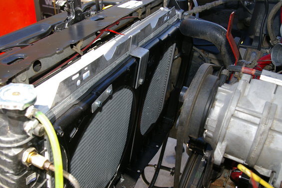 Close-up of a vehicle's radiator and dual electric fans, with hoses and engine components visible