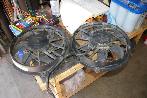 Two black electric fans with Ford logos on a wooden table