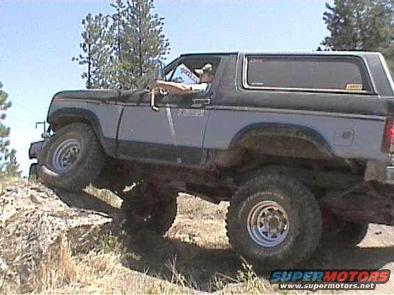 1985 Ford Bronco climbing a dirt hill with front wheel off the ground