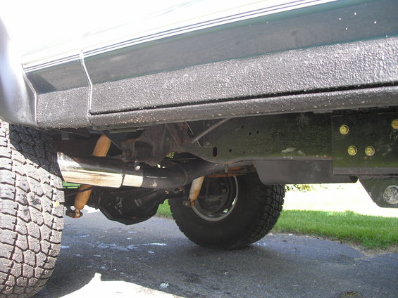 Close-up of a vehicle's undercarriage, showing the exhaust pipe, suspension, and tires