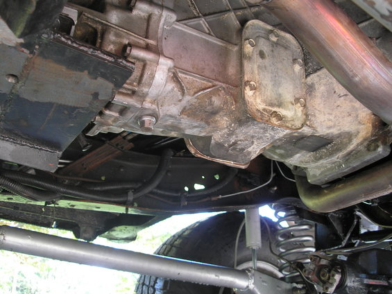 Underside view of a vehicle's transmission, exhaust pipe, and suspension components