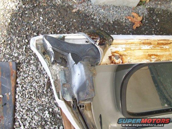 Close-up of a damaged door seal and rusted frame on a vehicle. Supermotors.net logo visible