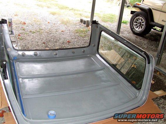 Interior of a removed Ford Bronco hardtop, with a Jeep visible in the background