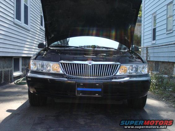 Black sedan front view, hood open. Chrome grille, clear headlights