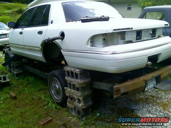 2002 Ford Crown Victoria on cinder blocks with fuel filler hose attached