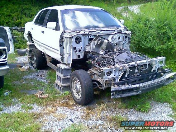 White sedan with front end removed, supported by cinder blocks
