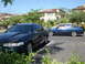 1992 Ford Taurus - A dark green sedan with an aftermarket hood scoop is parked in a lot next to a blue sedan.