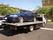 1992 Ford Taurus - A blue sedan with a rear spoiler is being transported on a tow truck.