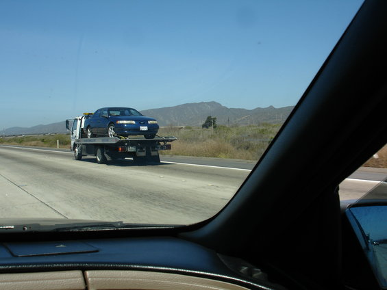 Blue 1992 Ford Taurus on a tow truck on a highway