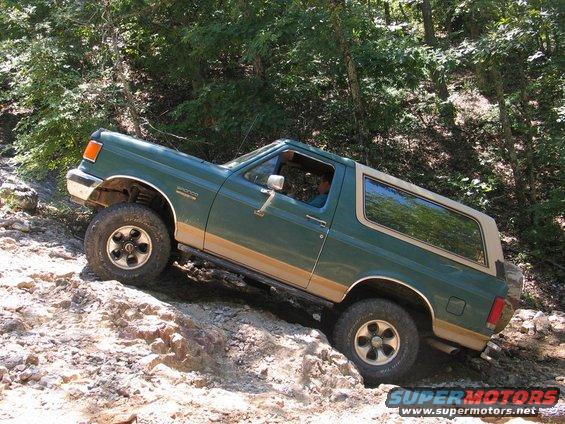 Green Ford Bronco with tan trim on rocky terrain