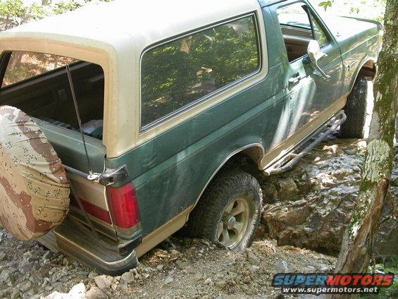 1990 Ford Bronco navigating rocky terrain, rear quarter view
