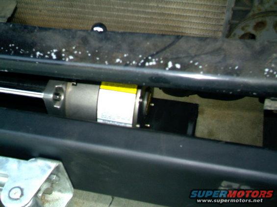 Black bumper with a silver cylinder and yellow label mounted underneath