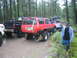 1990 Ford Bronco - Multiple off-road vehicles are stuck in deep mud in a wooded area.