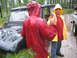 1990 Ford Bronco - People in rain gear stand near a vehicle stuck in the mud during a downpour.
