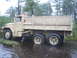 1990 Ford Bronco - A tan military truck navigates through a flooded area surrounded by trees.