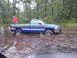 1995 Dodge 1500 - A blue pickup truck navigates through flooded terrain, with a person visible in the bed.