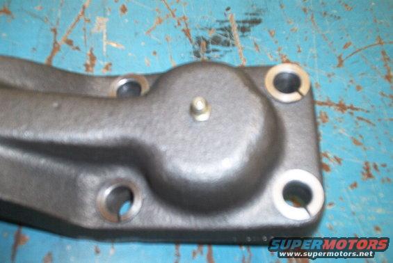 Metal steering arm component with bolt and washers on a blue surface
