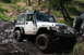 1995 Jeep Cherokee - A modified Jeep Wrangler TJ navigates a muddy off-road trail, with another vehicle partially visible.