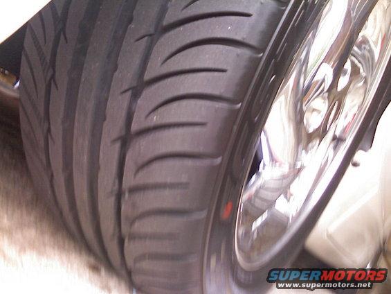 Close-up of a car tire tread and a shiny chrome wheel