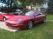 1995 Ford Probe - A red 1995 Ford Probe is seen parked in a driveway with other vehicles present.