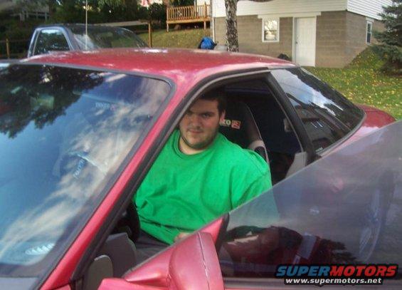 Red 1995 Ford Probe with a man inside, viewed from the passenger side