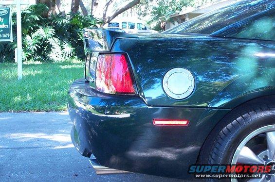 Rear quarter panel and taillight of a dark green 2001 Ford Mustang