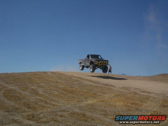 Brown 1985 Ford Ranger jumping mid-air with yellow bumper guard