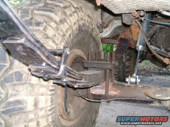 Close-up of a modified rear leaf spring suspension with a new U-bolt setup and shock absorber