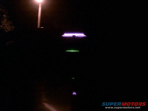 Car interior at night with purple and green glowing lights visible