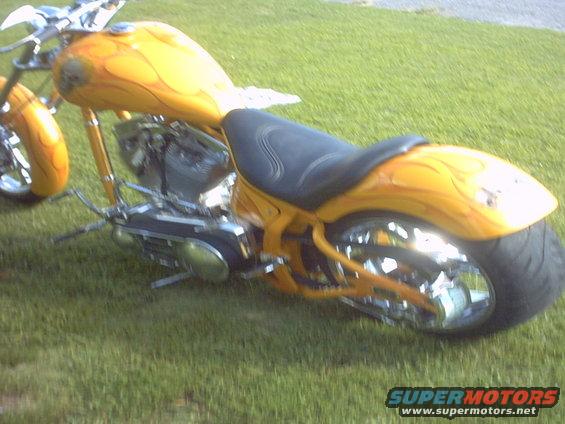 Yellow custom motorcycle with flame graphics, black seat, and chrome wheels, viewed from the right side