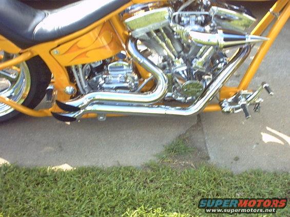 Yellow custom chopper motorcycle engine and frame with chrome exhaust pipes and flame decals on the tank