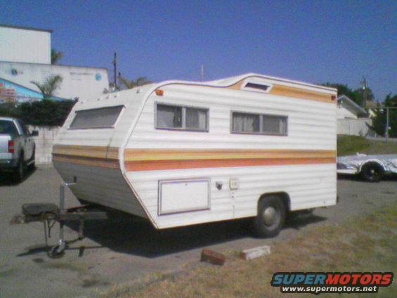 Travel trailer with orange and yellow stripes parked next to a pickup truck