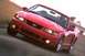 2003 Ford Mustang - A red 2003 Ford Mustang convertible is captured in a dynamic shot from the front three-quarter angle.